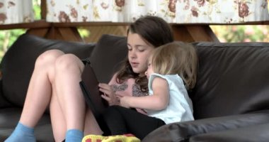 İki küçük kız kanepe terasta tablet bilgisayar kullanma