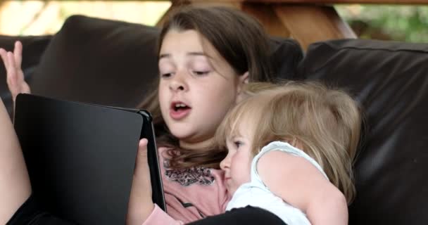 Två små flickor med Tablet PC på soffa på terrassen — Stockvideo