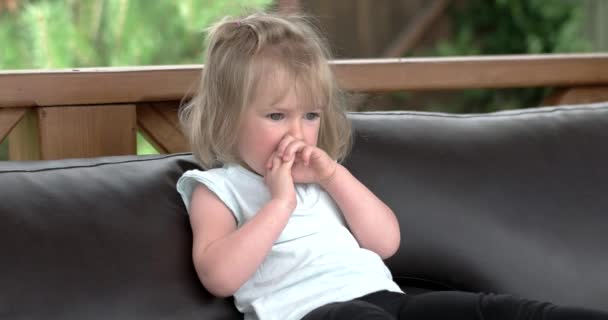 Pequena menina bonito assentos e sonhando no sofá no terraço — Vídeo de Stock