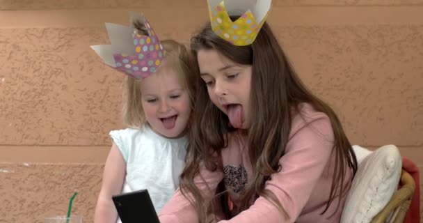 Twee schattige kleine zusters in kronen plezier met mobiele telefoon en het maken van grappige Selfie — Stockvideo