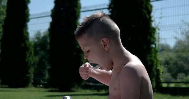 Ragazzo caucasico che mangia delizioso yogurt al parco . — Video Stock