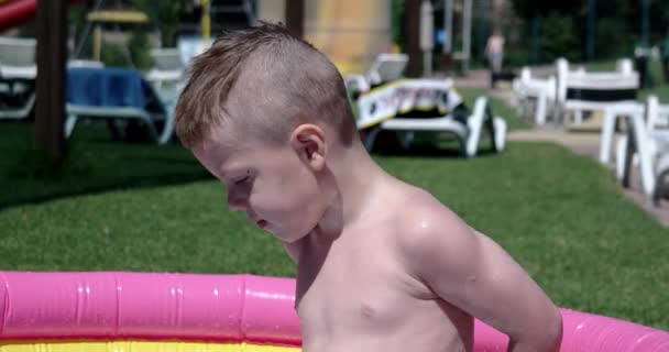 男の子遊び、晴れた日に緑の芝生の上の膨脹可能なプールで楽しんで — ストック動画