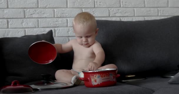 Liten kock pojke i köket leker med Pan, krukor och slev — Stockvideo