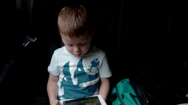 Menino usando um tablet sentado em um carro assento — Vídeo de Stock