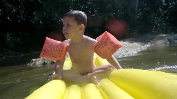 Chico joven que se divierte en colchón inflable en el río de la montaña — Vídeos de Stock
