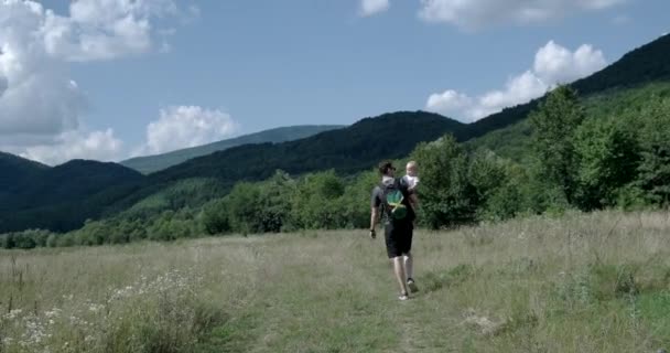 Petit enfant porté par son père à l'extérieur sur le terrain — Video