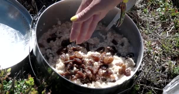Здоровий туристичних туристів сніданок вівсяна каша, родзинками і свіжого повітря в горах — стокове відео