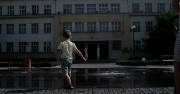 Fiatal fiú birtoklás móka Modern Splash szökőkút közelében — Stock videók