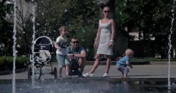Vonzó fiatal kaukázusi családi élvezi nyári nap Splash szökőkutat közelében — Stock videók