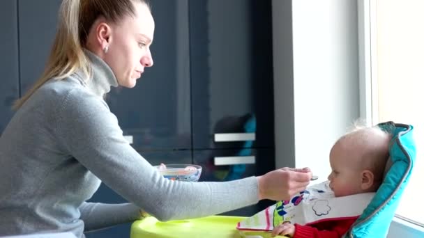 Kinder und Ernährung, Mutter füttert Baby in der heimischen Küche — Stockvideo