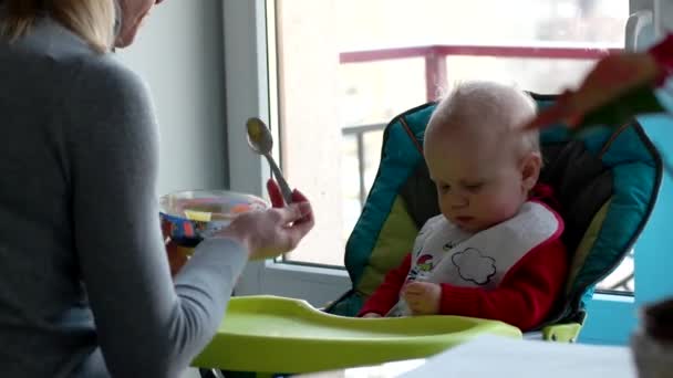 Τα παιδιά και τη διατροφή, μητέρα σίτιση το μωρό στην κουζίνα στο σπίτι — Αρχείο Βίντεο