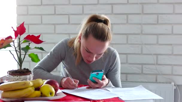 Mladá hospodyňka s dokumenty na mobil u stolu v domě — Stock video