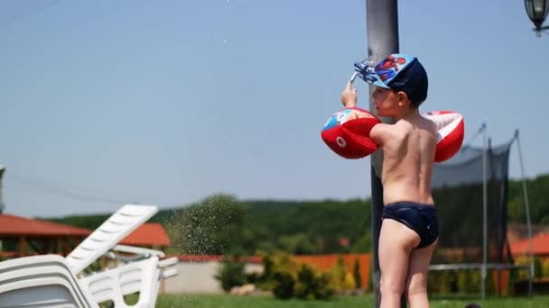 Adorável menino brincando com um chuveiro ao ar livre — Vídeo de Stock