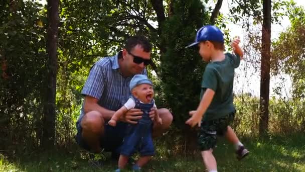 Junger kaukasischer Vater mit seinen kleinen Söhnen, die zusammen draußen Spaß haben — Stockvideo