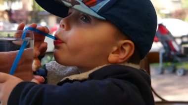 Küçük çocuk içecekler suyu kamışla masada otururken