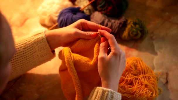 Femme assise et tricotant belle écharpe orange, gros plan — Video