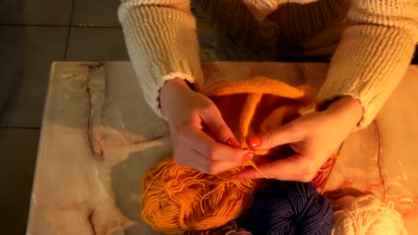 여 자가 앉아서 아름 다운 오렌지 스카프, 뜨개질을 닫습니다. — 비디오
