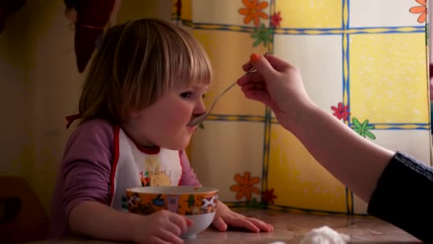Mutter füttert ihr kleines Mädchen mit einem Löffel. Mutter gibt ihrem entzückenden einjährigen Kind zu Hause Essen. — Stockvideo