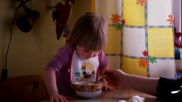 Moeder haar Baby Girl met een lepel voeden. Moeder geven voedsel aan haar schattige één-jarige kind thuis. — Stockvideo