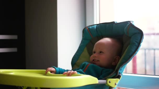 Baby sitter på ett barn lite bord. Mamma matar barnet med gröt. — Stockvideo