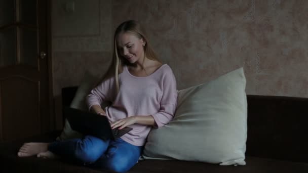 Kvinna sitter på soffan och använder bärbar dator — Stockvideo