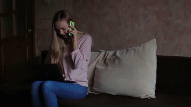Женщина сидит на диване и использует ноутбук — стоковое видео