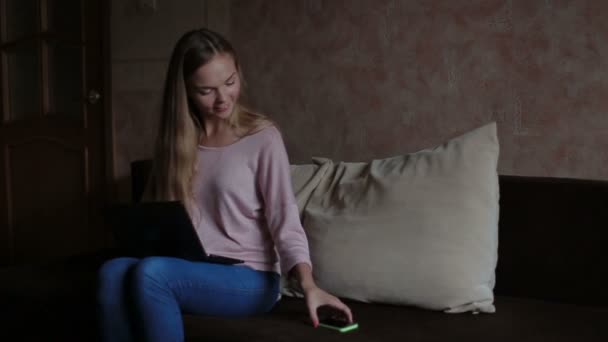 Kvinna sitter på soffan och använder bärbar dator — Stockvideo