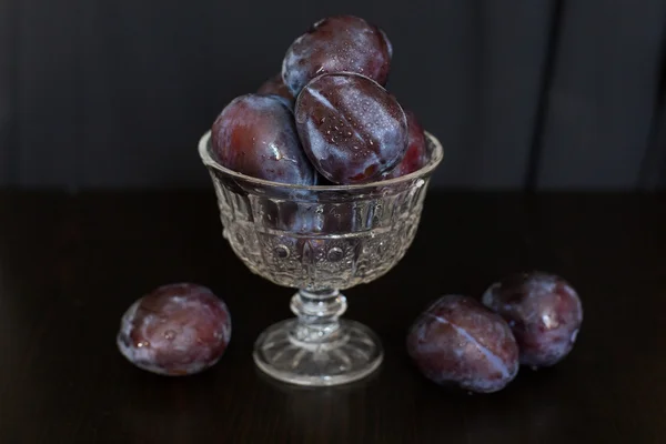 Plum pada latar belakang gelap dalam vas kaca — Stok Foto