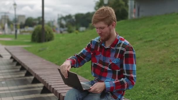 年轻人在公园里的笔记本电脑上工作 — 图库视频影像
