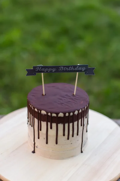 Chocolade taart met verjaardag naakt op een achtergrond van bladeren met een witte crème Stockfoto