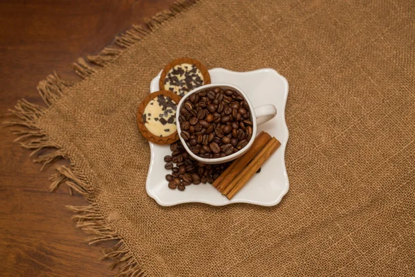 Grãos de café canela biscoito copo branco e pires — Fotografia de Stock