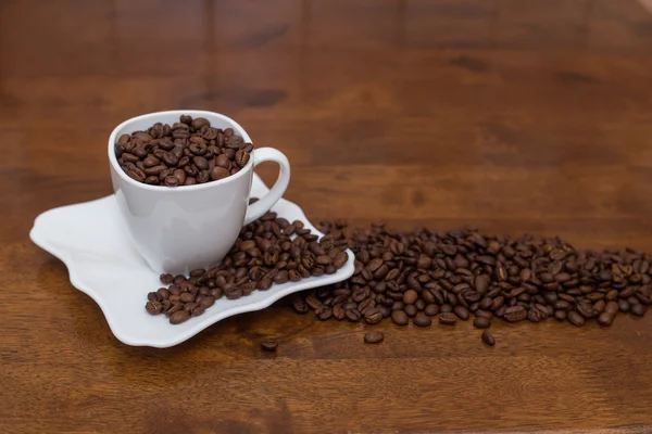 Hamburan biji kopi cangkir putih dan piring — Stok Foto