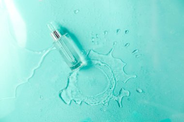 Sıvı kolajen ve hiyalüronik asit içeren cam şişe, hidrasyon derisi. Üst düz görünüm telif uzayı. Soyut su arkaplanı.