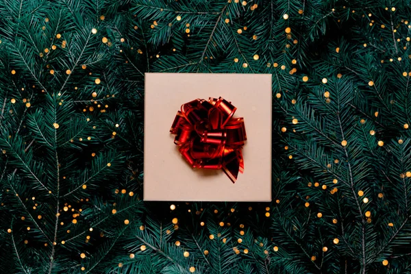 Χριστουγεννιάτικο δώρο με bokeh φώτα και κορδέλα σε εορταστικό φόντο έλατο. Κορυφαία οριζόντια άποψη copyspace — Φωτογραφία Αρχείου