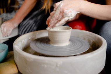 Çömlekçi çarkının üzerinde çömlek kupası yapan kadın eller. El yapımı ve el yapımı konsept.