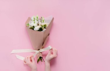 Çiçekçi kadın çiçek buketi yapıyor. Adım adım icraat. Üst yatay görünüm telif alanı soyut pembe arkaplan