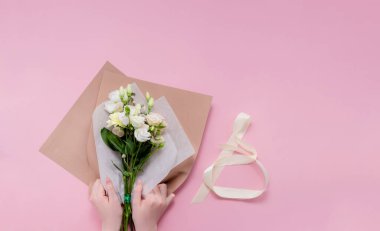 Çiçekçi kadın çiçek buketi yapıyor. Adım adım icraat. Üst yatay görünüm telif alanı soyut pembe arkaplan