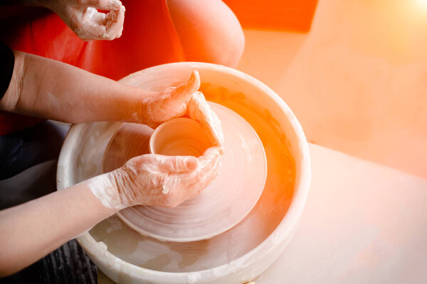 Female hands crafting a pottery cup on a potter's wheel. Handmade and crafting concept.