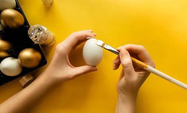 DIY Mãos femininas colorir ovos de Páscoa e decoração com ouro. Visão horizontal superior copyspace — Fotografia de Stock