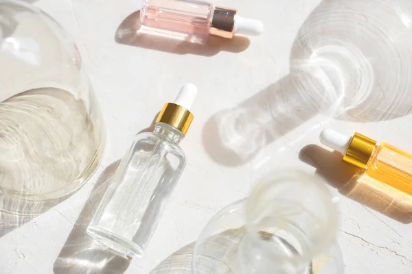 Cam şişelerde pipet damlacıklı eko mineral yağı. Şeffaf hyaluronik serum jeli ve cilt bakımı konsepti. Üst yatay görünüm telif uzayı