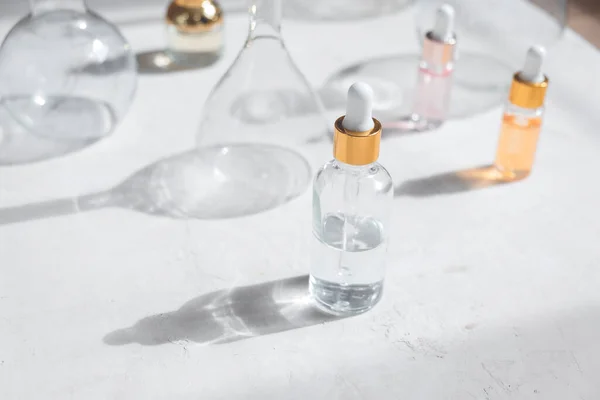 Cam şişelerde pipet damlacıklı eko mineral yağı. Şeffaf hyaluronik serum jeli ve cilt bakımı konsepti. Üst yatay görünüm telif uzayı
