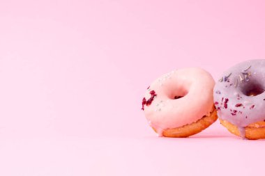 Donutları krema ve şekerle baştan çıkarmak. Farklı tatlarda tatlı, yuvarlak çörekler. Üst yatay görünüm telif uzayı. Sağlıklı beslenme ve abur cubur