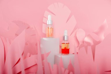 Beyaz bir podyumda üzerinde pipeti olan damlatan cam şişeler. Şeffaf hyaluronik doğal güzellik mineral ürünü ve eko serumu cilt bakımı kavramı.