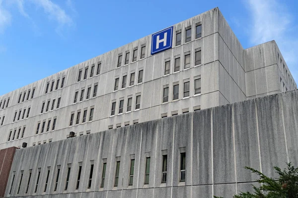 Hastane için H işareti olan büyük gri beton bina.