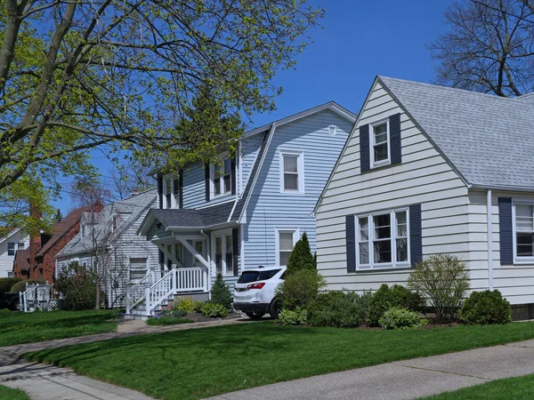 Residential street with modest detached houses with aluminum siding or clapboard