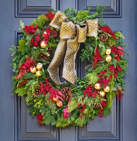front door with Christmas wreath made of pine branches, pine cones, red berries, and golden apples