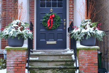 Ön kapıda kırmızı fiyonklu Noel çelengi