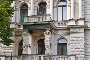 Süvari heykelleri olan Neoklasik villa. Mimari destek görevi gören heykel gibi bir kadın figürü.