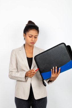 Ofisteki kadın elinde bir dosya, kalem ve sunum tutuyor. Resmi giyinmiş genç bir kadın beyaz arka planda beyaz ceket giyiyor..