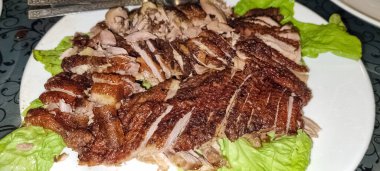 Meyveli, kıtır kıtır, kavrulmuş ördek. Beyaz bir tabakta taze yeşil marul yatağında. Mutfak, gurme, restoran ve yemek dağıtım temaları için mükemmel..